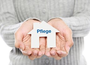 Hände halten ein kleines Haus mit der Aufschrift „Pflege“ – Symbol für Organisation der Pflege zu Hause und Entlastung im Alltag | © PflegeBetreuer | unabhängige Pflegeberatung