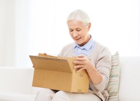 Ältere Frau freut sich über ein PflegePaket mit kostenlosen Pflegehilfsmitteln für die häusliche Pflege | © PflegeBetreuer | unabhängige Pflegeberatung
