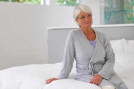 Fallbeispiel: Frau Berger stellt einen Antrag auf Pflegeleistungen | © PflegeBetreuer | unabhängige Pflegeberatung Ältere Frau sitzt nachdenklich auf dem Bett und blickt zur Seite | © PflegeBetreuer | unabhängige Pflegeberatung